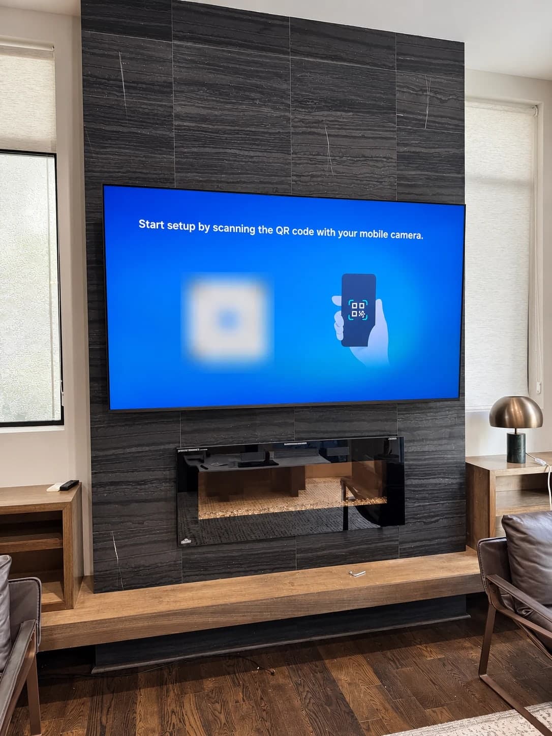 Large flat-screen TV mounted on a dark stone-tile wall, centered above a built-in fireplace